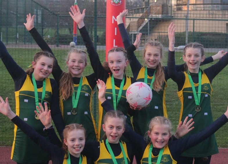 U13 netball team pose with gold medals at Millfield School netball tournament